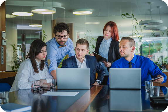 Team of IT professionals collaborating around laptops in a modern office